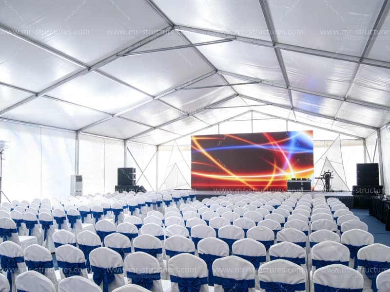 Interior of outdoor event tent set up for conference with stage and LED screen
